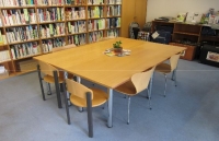 Großer Tisch mit Stühlen vor einem vollen Bücherregal
