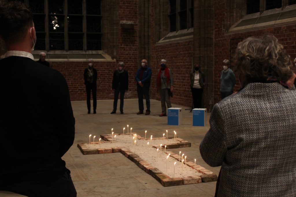 Viele Menschen stehen im Kreis um ein Kreuz mit angezündeten Kerzen zur Eröffnung der Austellung Bremen - Stadt der Menschenrechte