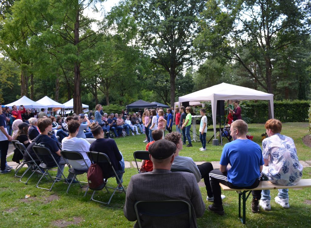 Schulklasse tritt vor vielen Zuschauern im Garten der Menschenrechte während des Kultur Mitmach Marktes auf