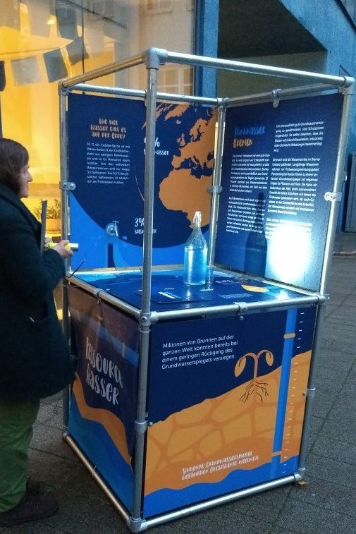 Besucherin der Ausstellung betrachtet den Ausstellungsturm zum Thema "Wasser für alle"