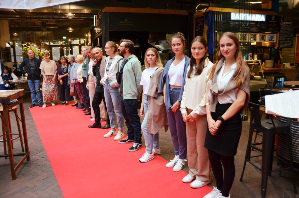 Viele junge Personen stehen nebeneinander an einem roten Teppich bei der fairen Woche 2022