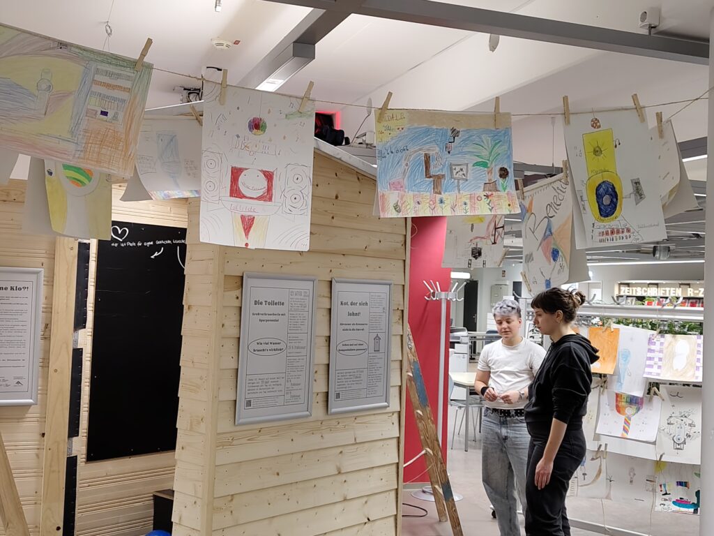 Ausstellung Ein Leben ohne Klo und zwei Macher:innen der Ausstellung