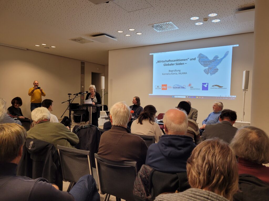 Sprecherin auf dem Podium. Publikum im Vordergrund.